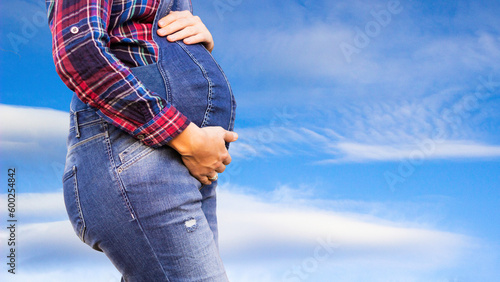 A pregnant woman's tender touch amidst the vast sky