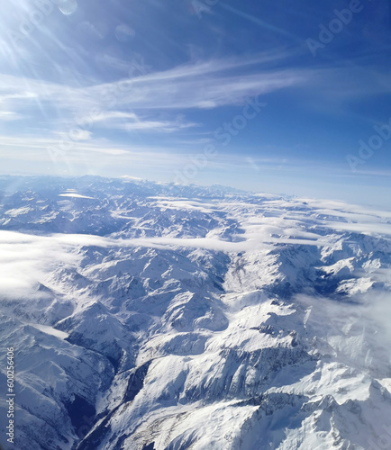 View from the airplane cabin to the sky, clouds and Alps in the snow