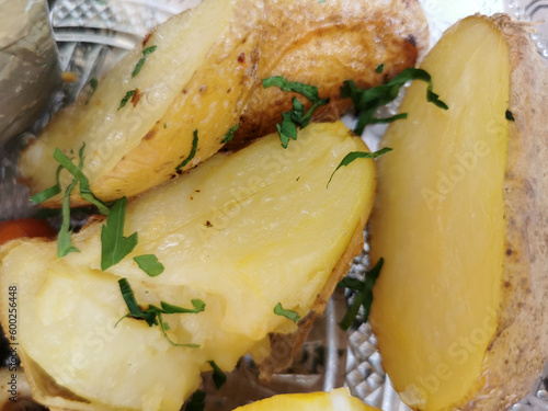 Serving of boiled whole young potatoes with butter, sprinkled with fresh chopped dill on the table, top view close-up in selective focus