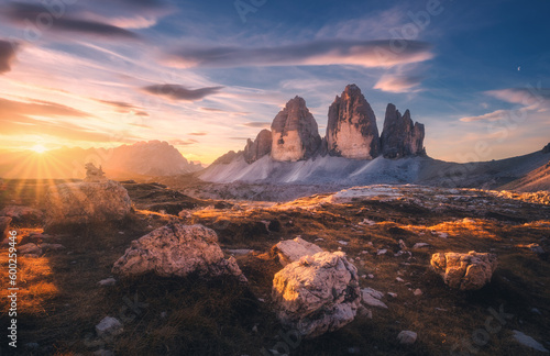 Rocks and stones at sunset in autumn in Tre Cime  Dolomites  Italy. Colorful landscape with mountains  trail  orange grass  blue sky with clouds  golden sunlight in fall. Hiking in mountains. Nature