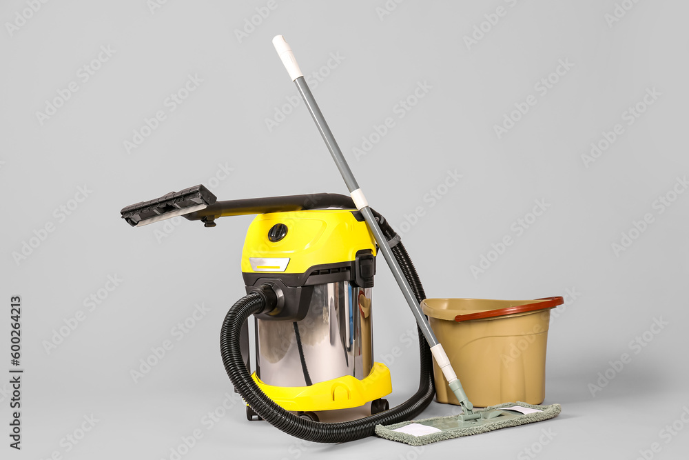 Vacuum cleaner with mop and bucket on grey background Vacuum cleaner with mop and bucket on grey background
