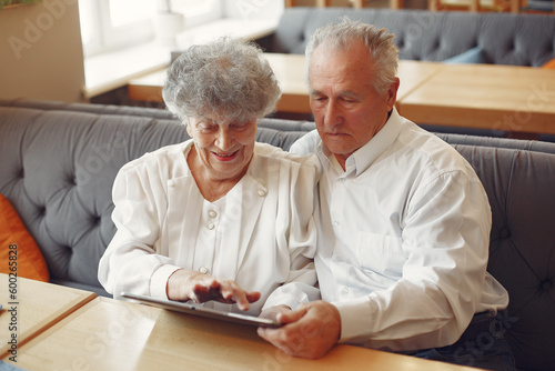 Elegant old couple in a cafe using a tablet