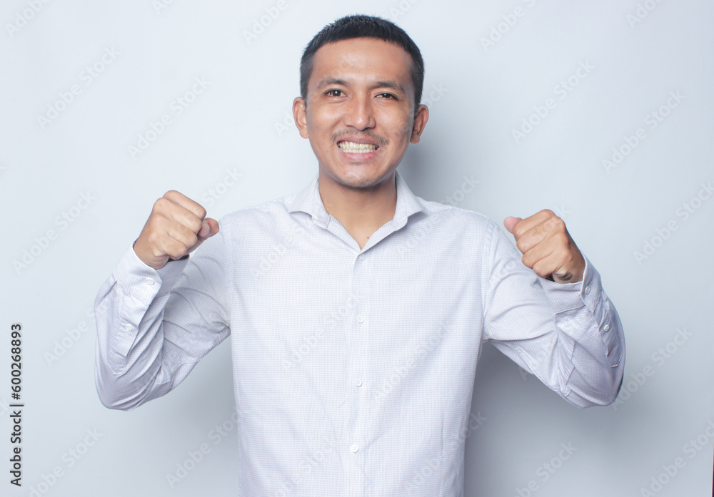 Asian man wearing a white shirt showing strong gesture by lifting her arms and muscles smiling proudly on the white background. Asian man wearing a white shirt showing strong gesture by lifting her arms and muscles smiling proudly on the white background.