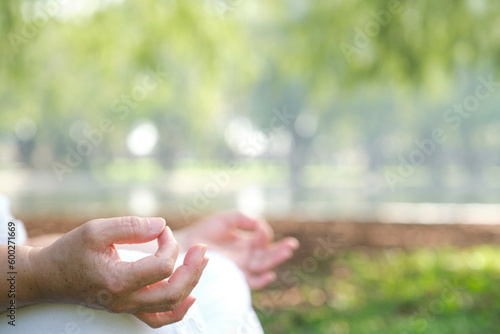 Detail of an unrecognizable woman practicing yoga or meditation, hands in mudra position, in a natural environment. Concepts: wellness, calmness and mental health.