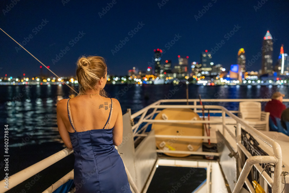 Young woman on a boat viewing the illuminated Cleveland skyline in the background. Young woman on a boat viewing the illuminated Cleveland skyline in the background.