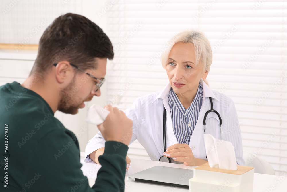 Sick patient with napkin and doctor at table in clinic Sick patient with napkin and doctor at table in clinic