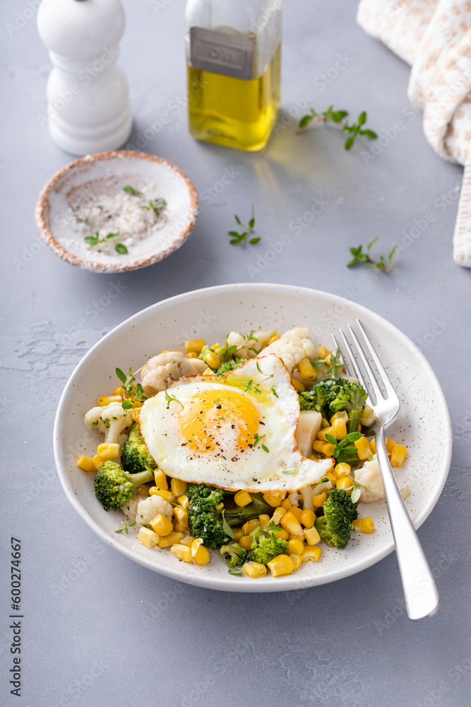 Healthy breakfast bowl with cooked vegetables and fried egg