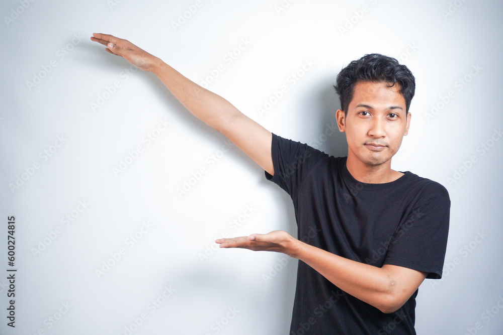 Young handsome man over isolated background pointing to the side to present a product Young handsome man over isolated background pointing to the side to present a product