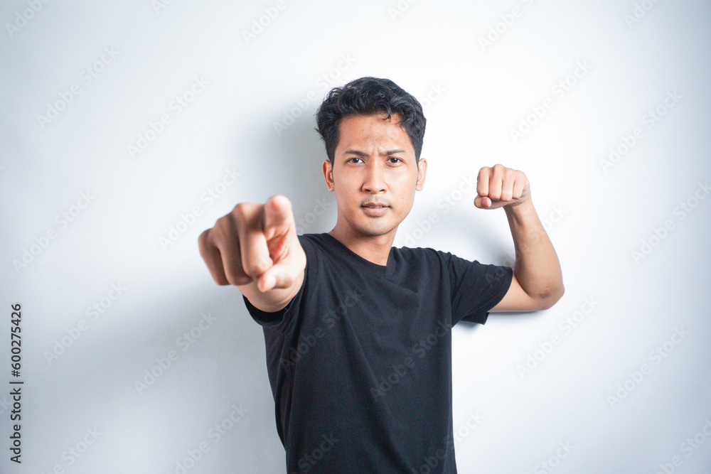 Asian young man in black t-shirt pointing forward, Looking at Camera, make choosing you gesture against white background Asian young man in black t-shirt pointing forward, Looking at Camera, make choosing you gesture against white background
