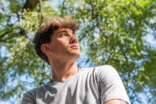 Side view of a young man who is looking up over nature background