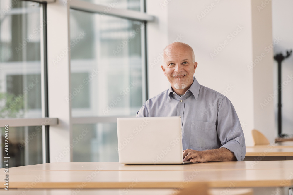 Elderly gentleman makes funny faces using a laptop