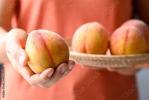 Ripe Peaches fruit in basket holding by woman hand