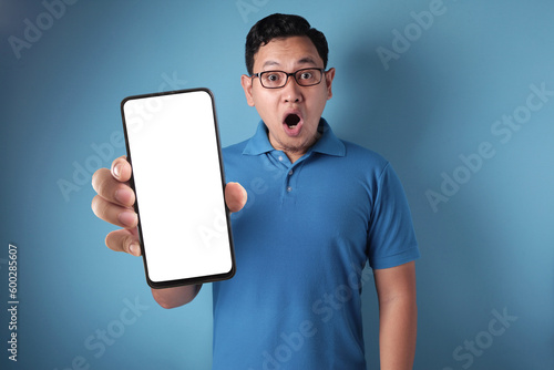 Asian man looking to camera, smiling and showing empty blank white copy space phone mock up template