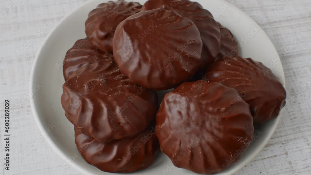 Marshmallows in chocolate glaze on a white saucer. Close-up of chocolate marshmallows on a white plate lying on a light table. The concept of confectionery sweets Marshmallows in chocolate glaze on a white saucer. Close-up of chocolate marshmallows on a white plate lying on a light table. The concept of confectionery sweets