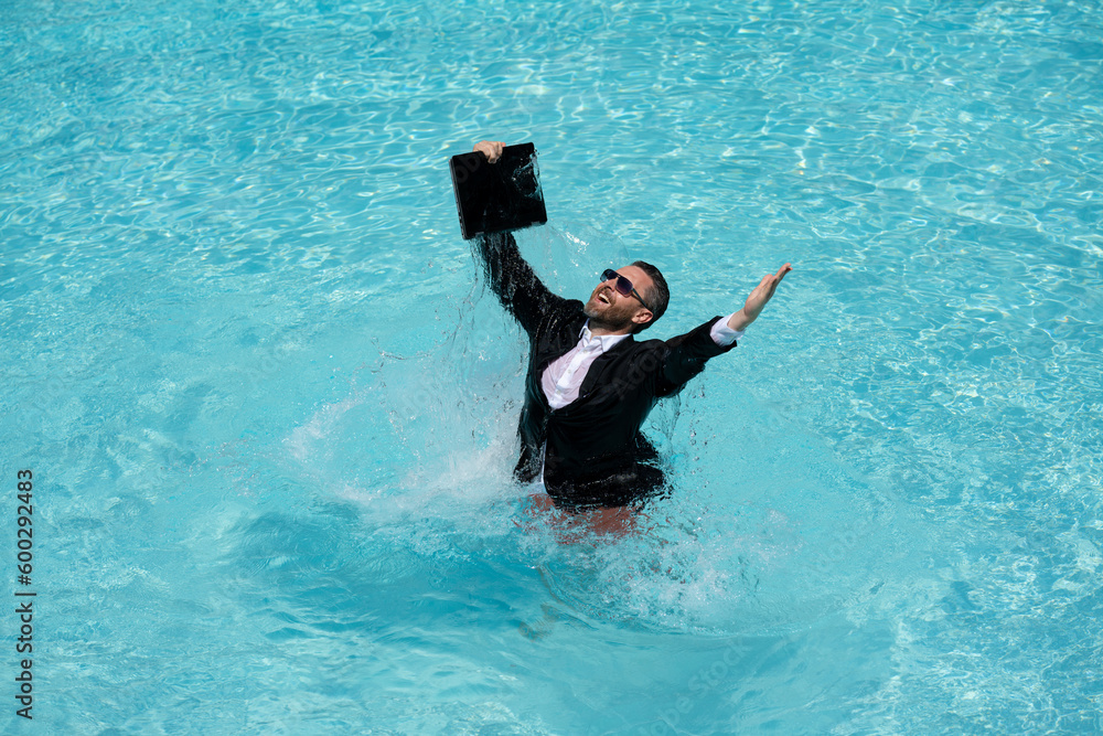 Successful business man in suit in pool water. Business man in suit working on laptop in swimming pool. Travel tourism and business concept. Crazy male office business employee using laptop.