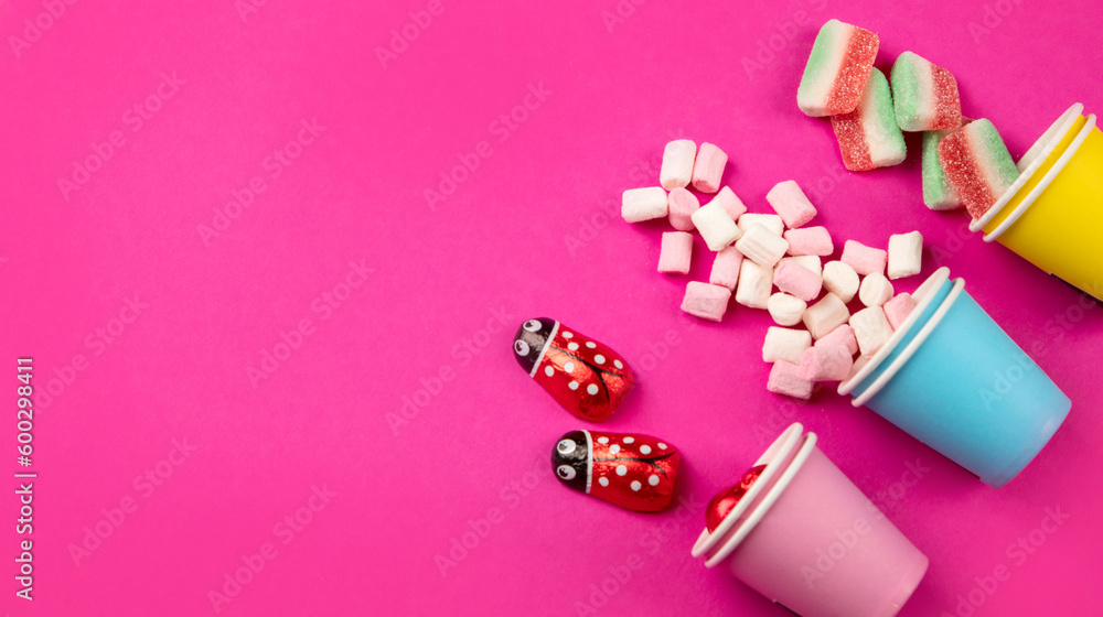 Paper cups with different candies on pink background. Paper cups with different candies on pink background.