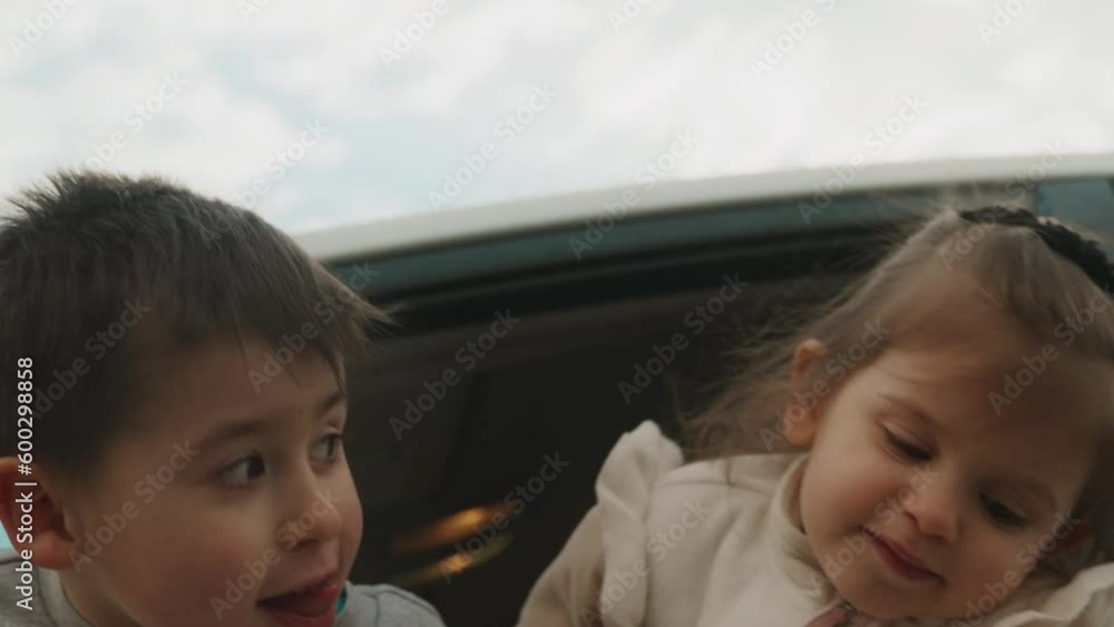 Little boy and baby girl sitting in the front seat of a white car and looking down at the asphalt, sticking their heads out the window car. Road trip. Little boy and baby girl sitting in the front seat of a white car and looking down at the asphalt, sticking their heads out the window car. Road trip.