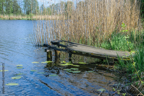 Spalony drewniany pomost położony nad wodą  w jeziorze służący do połowu ryb , palić za sobą mosty