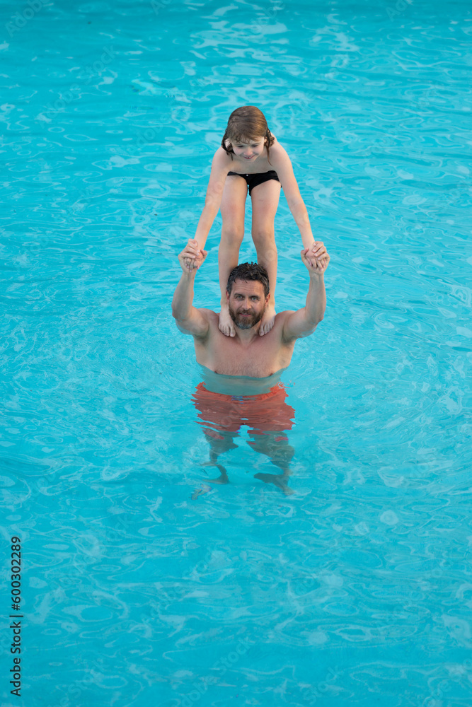 Father and son have fun in pool. Dad with child splashing in pool water. Father and son playing together in swimming pool. Dad and little kid swimming in summer swimming pool. Family summer vacation.
