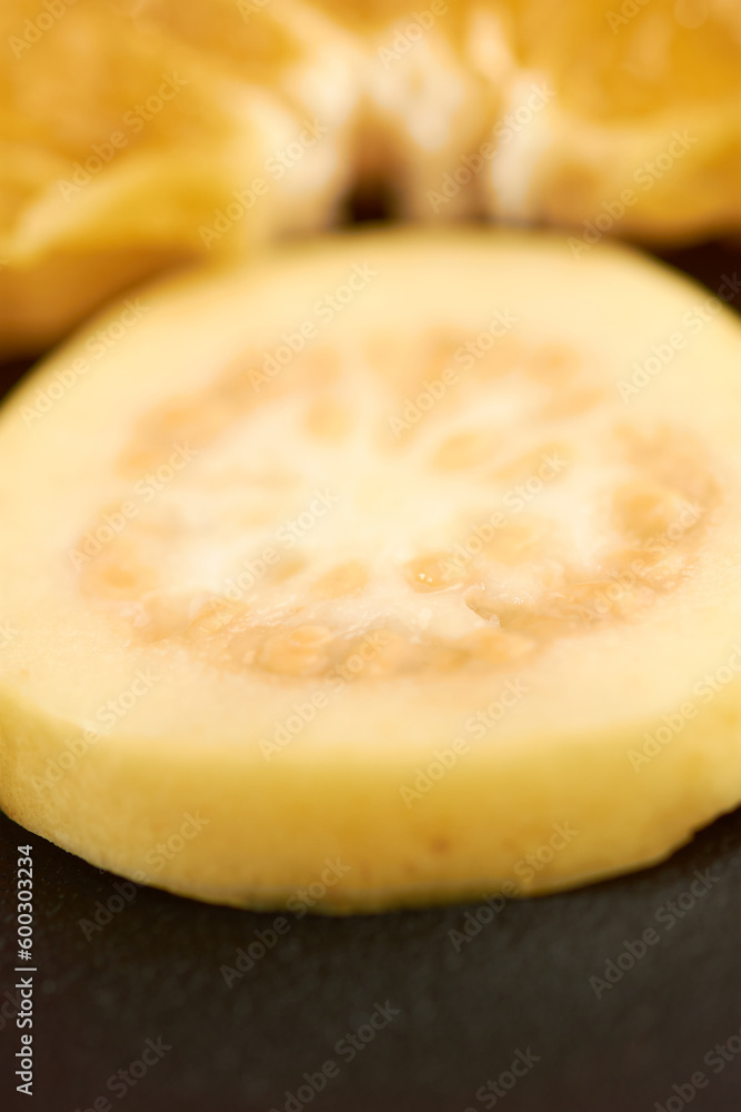 Guava in close-up, with a blur of a fruit bowl.