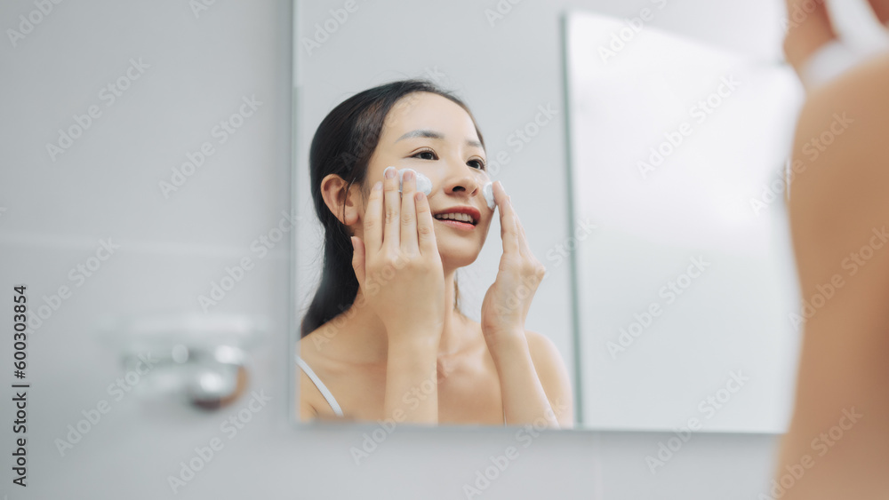 Beautiful woman cleaning her face with a foam treatment in bathroom Beautiful woman cleaning her face with a foam treatment in bathroom