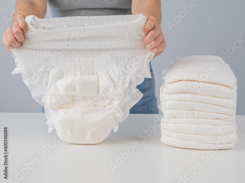 A woman chooses an adult diaper from a pile. Urinary incontinence problem. photo