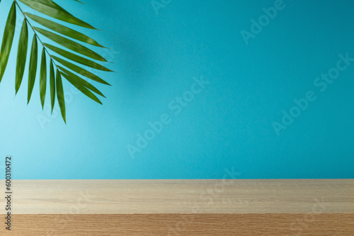 Empty wooden table with palm tree leaf over blue background . Summer mock up for design and product display
