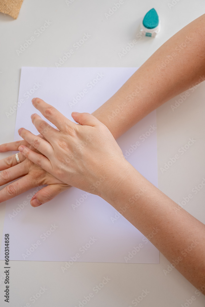 top view of a woman's hands pressing a rubber stamp on a blank sheet of paper.
