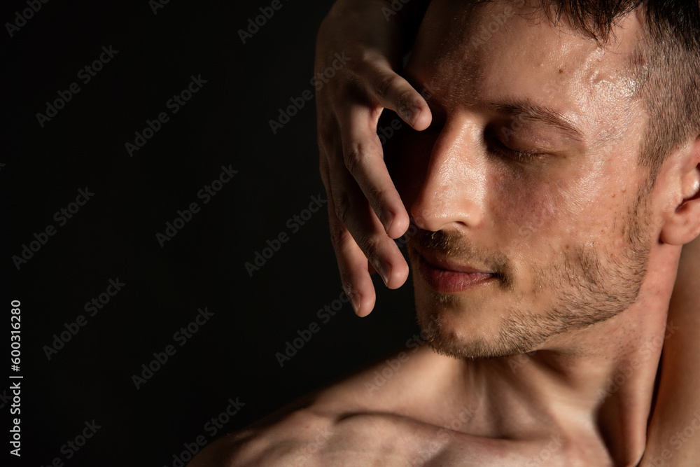Naklejka premium Young attractive man with an athletic body on a black background.