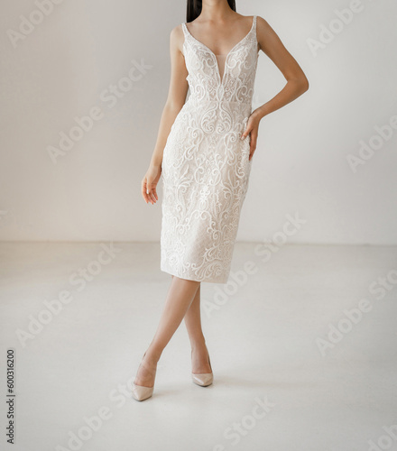 Classic short white wedding dress with cleavage decorated with floral lace. Bride dressed in the sleeveless white wedding dress with deep neckline