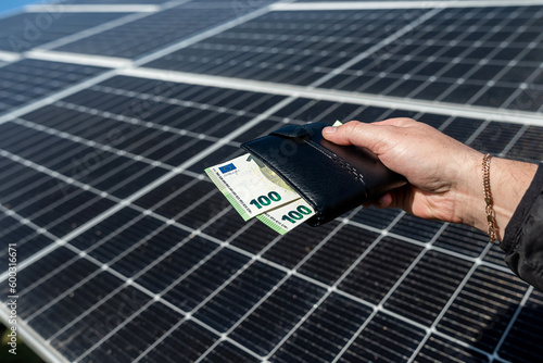 Vászonkép close-up of hands holding euro money in wallet over solar panels on their background