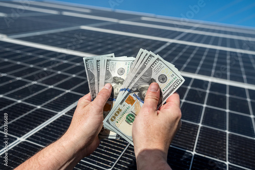 wonderful worker holds round amount of money for the installation of solar panels in his hands