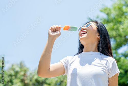 Portrait of beautiful Asian woman eating ice cream in summer at park