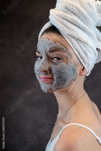 Female face with cosmetics cleansing gray bubble mask on dblack background photo