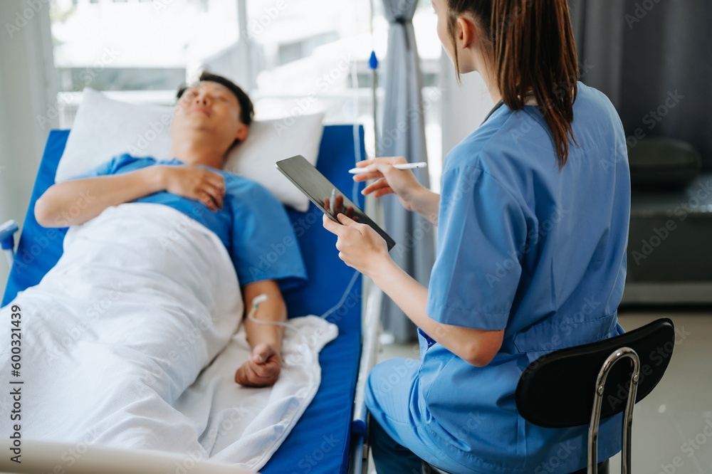 Doctor in white suit take notes while discussing and Asian elderly, man patient who lying on bed with receiving saline solution in hospital or clinic. Doctor in white suit take notes while discussing and Asian elderly, man patient who lying on bed with receiving saline solution in hospital or clinic.