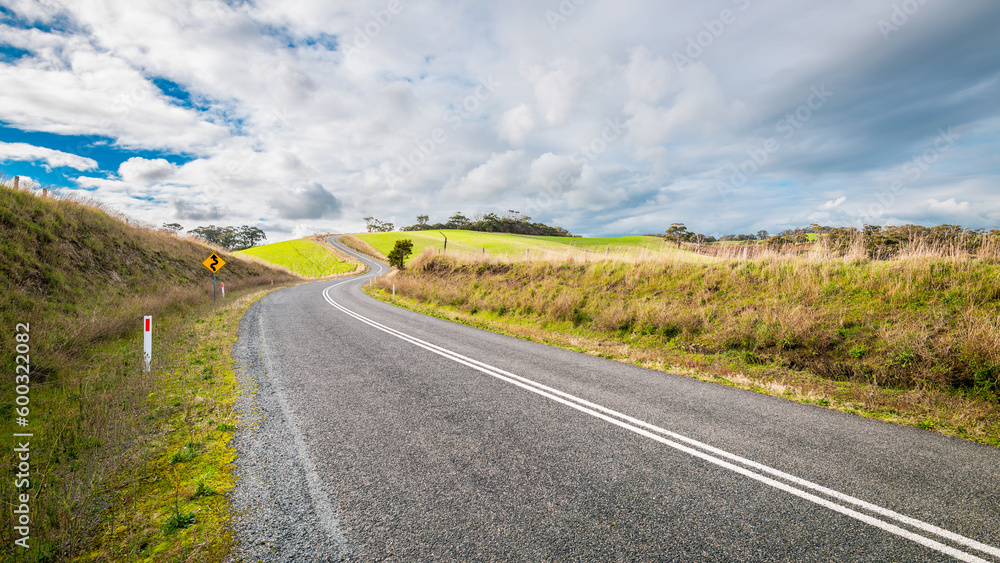 Winding empty road going up-hill through Adelaide Hills farmland during winter season, South Australia