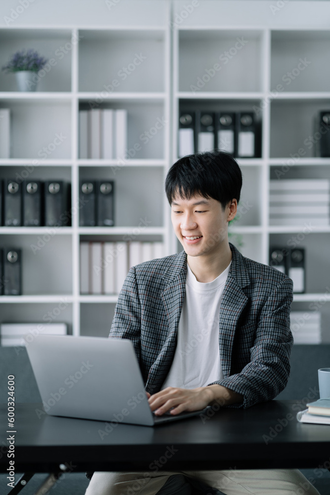 Young Asian businessman working at office with laptop and documents on table. Young Asian businessman working at office with laptop and documents on table.