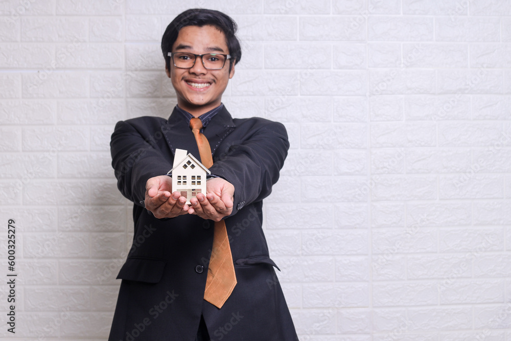 Property agent wearing suit showing home mock up on hands Property agent wearing suit showing home mock up on hands