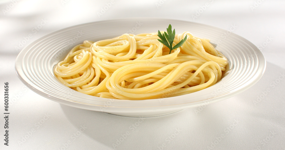 spaghetti on a plate. aglio e olio garlic and oil pasta. yellow noodles with parsley leaf. cooked pasta on a light background. Italian dish close-up. mediterranean cuisine. sunny day. spaghetti on a plate. aglio e olio garlic and oil pasta. yellow noodles with parsley leaf. cooked pasta on a light background. Italian dish close-up. mediterranean cuisine. sunny day.