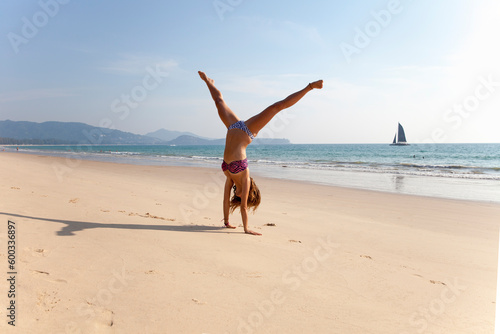 Young woman in bikini practicing handstand at beach photo