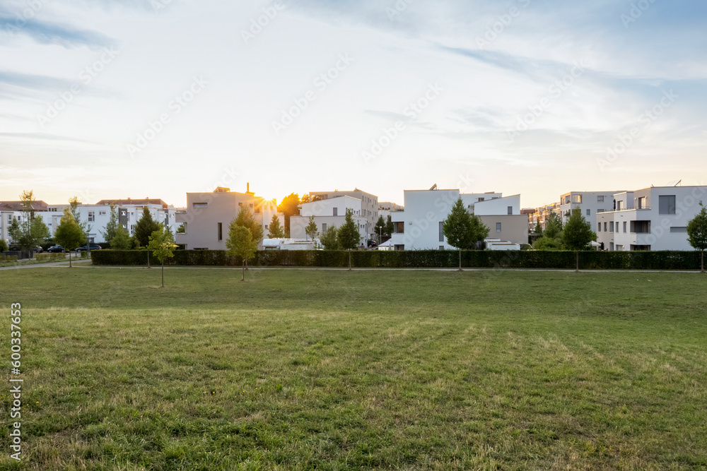 Germany, Bavaria, Augsburg, Grassy area in front of new modern suburban flats at sunset Germany, Bavaria, Augsburg, Grassy area in front of new modern suburban flats at sunset