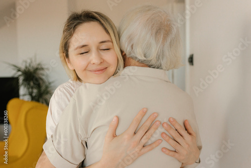 Smiling woman embracing grandmother at home photo