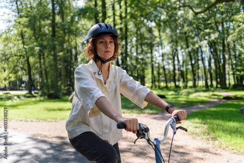 Young woman in helmet riding on bicycle at park