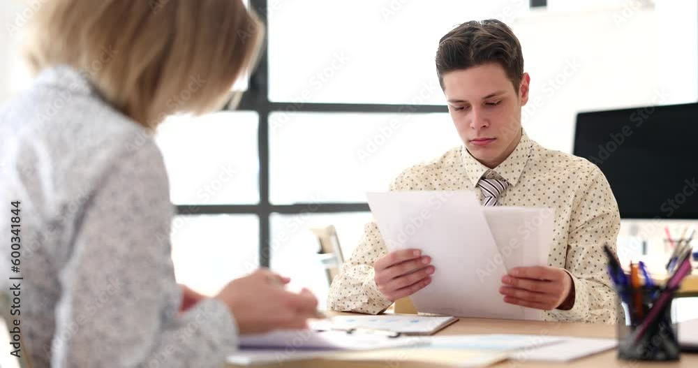 Serious business partners colleagues are sitting at table. Discussing documents and managers are reading sales report Serious business partners colleagues are sitting at table. Discussing documents and managers are reading sales report