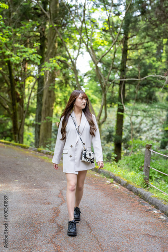 白いジャケットを着た女性が森の中を歩く風景 Woman in white jacket walking in the forest