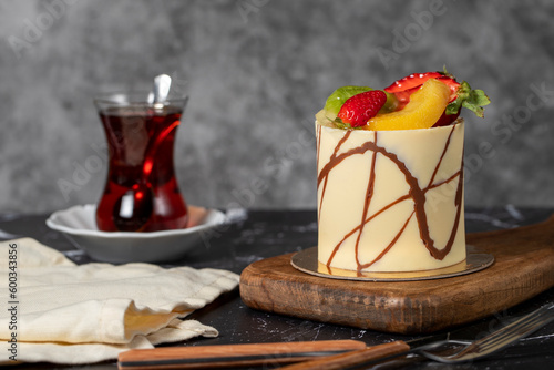Cream cake covered with fruit and chocolate. Fruit cake on a dark background