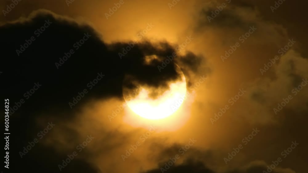 Close up, slow moving dark clouds moving across bright glowing sun. Close up, slow moving dark clouds moving across bright glowing sun.