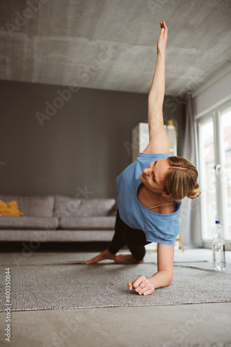 Young blonde woman doing yoga in her apartment