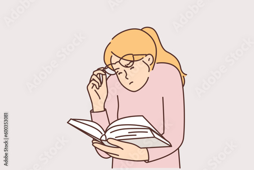 Woman is reading book lifting glasses and squinting eyes due to problems caused by poor vision