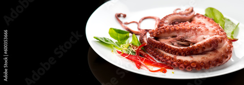 Octopus serving with vegetables, sea food. Freshly boiled octopus on a white plate, Mediterranean cuisine, dinner. Border design on black background